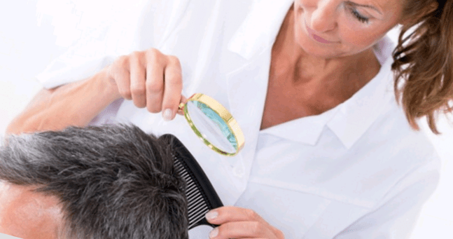 doctor examines psoriasis of the head